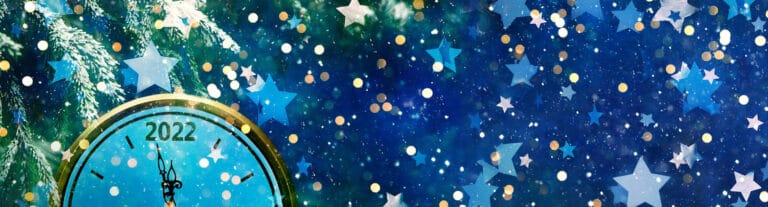 old fashioned analog clock almost midnight 2022 with snow, stars and glitters floating through the image