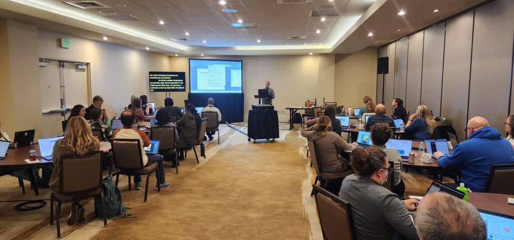 Chad Chelius gives a presentation on accessible documents to a crowd of about 25 people in a conference hall.