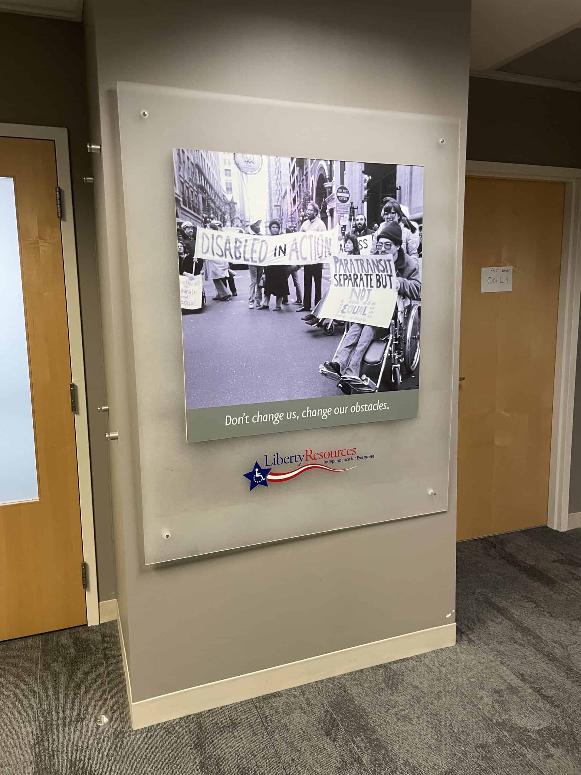 A poster showing people with disabilities protesting, with the following quote underneath. "Don't change us, change our obstacles."