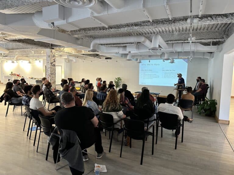 A large group of Tamman employees gather around for a presentation.