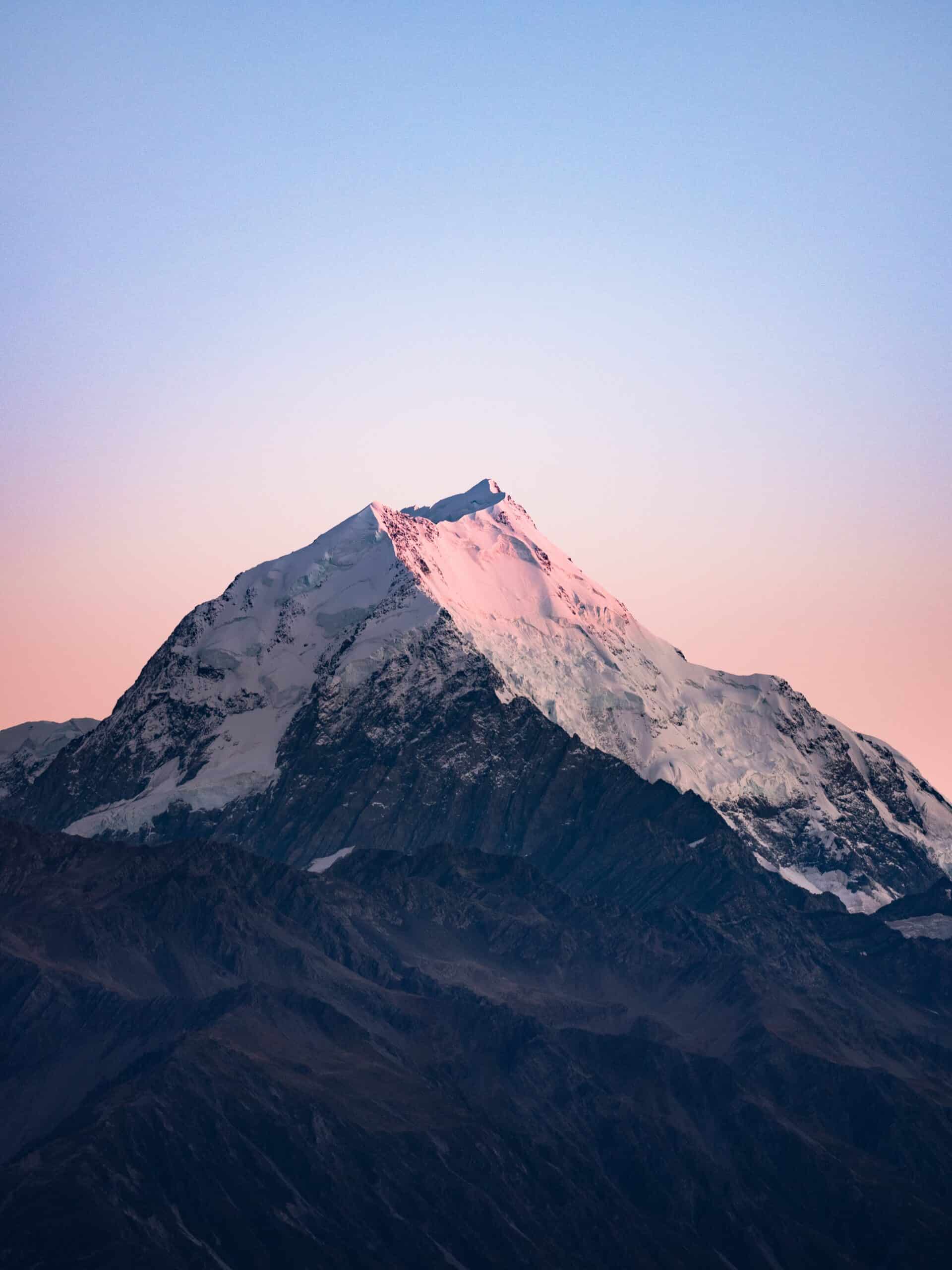 Snowcapped mountain at sunrise with blue sky above