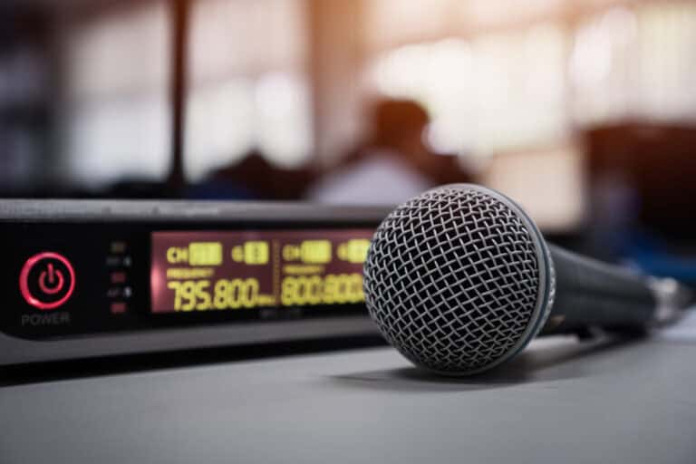 Recording microphone with an audio mixer with green alarm clock style numbers showing audio levels.