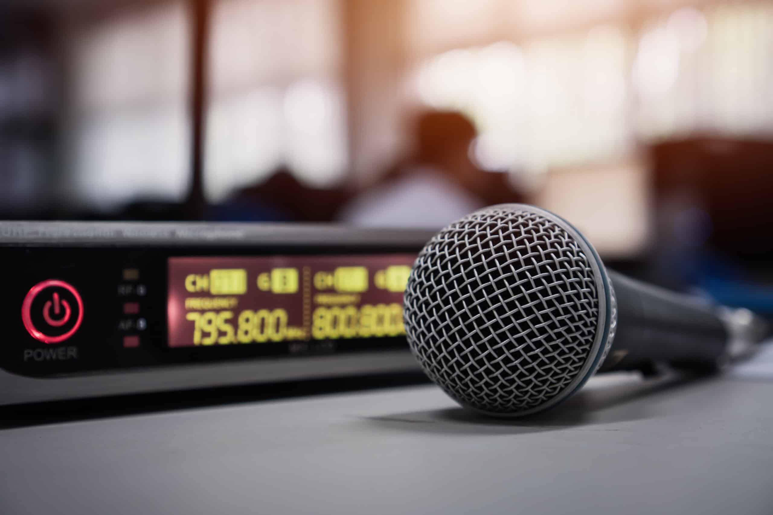 Recording microphone with an audio mixer with green alarm clock style numbers showing audio levels.