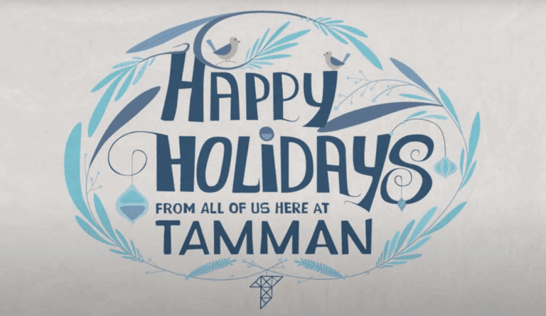 A light and dark blue holiday card graphic reads "Happy Holidays from all of us here at Tamman". The graphic includes lovely bluebirds, branches, rounded ice crystals, and the Tamman "T" logo.