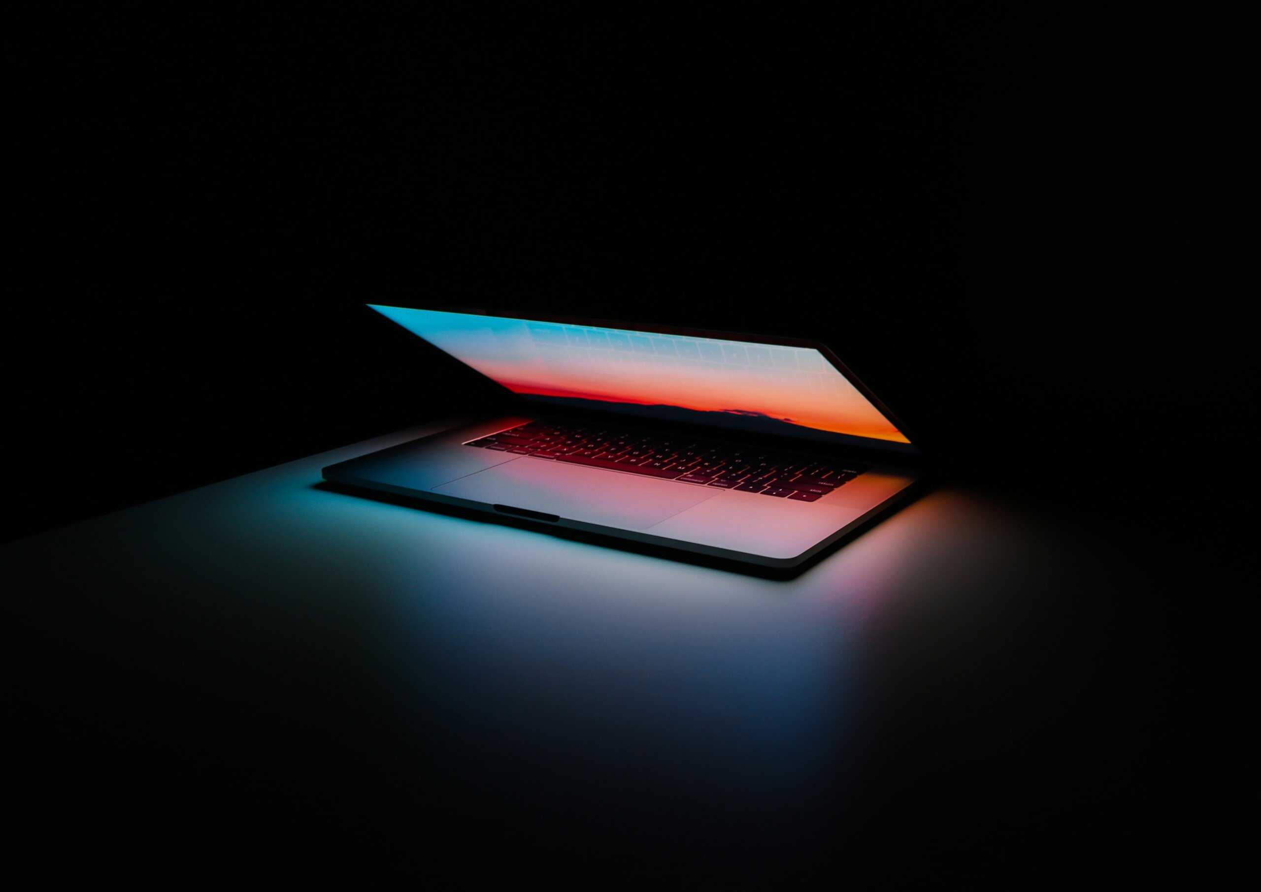Half open colorful laptop screen set against a black backdrop