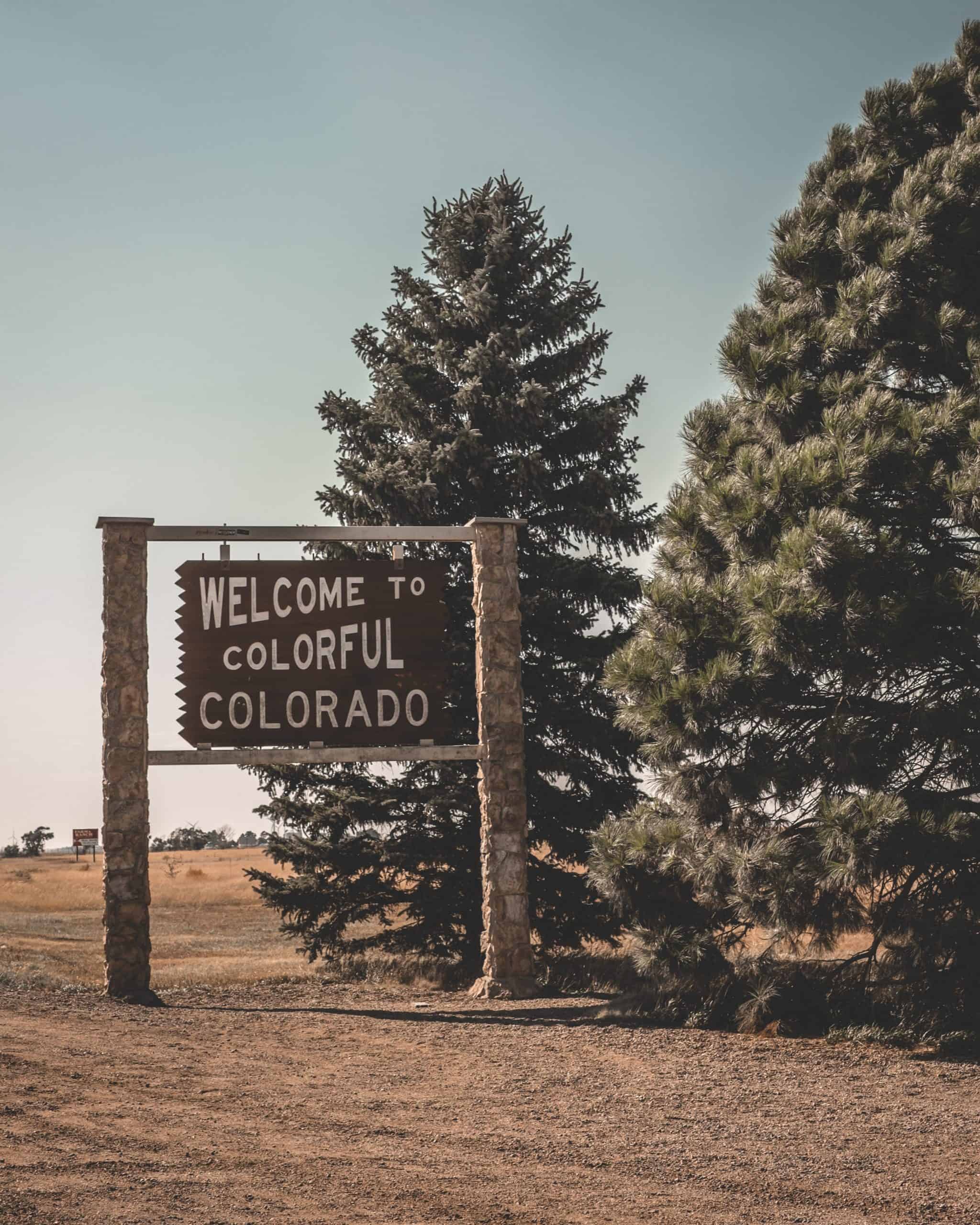 Sign that says 'welcome to colorful Colorado' next to two trees