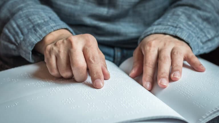 A person reads from a book printed in braille.
