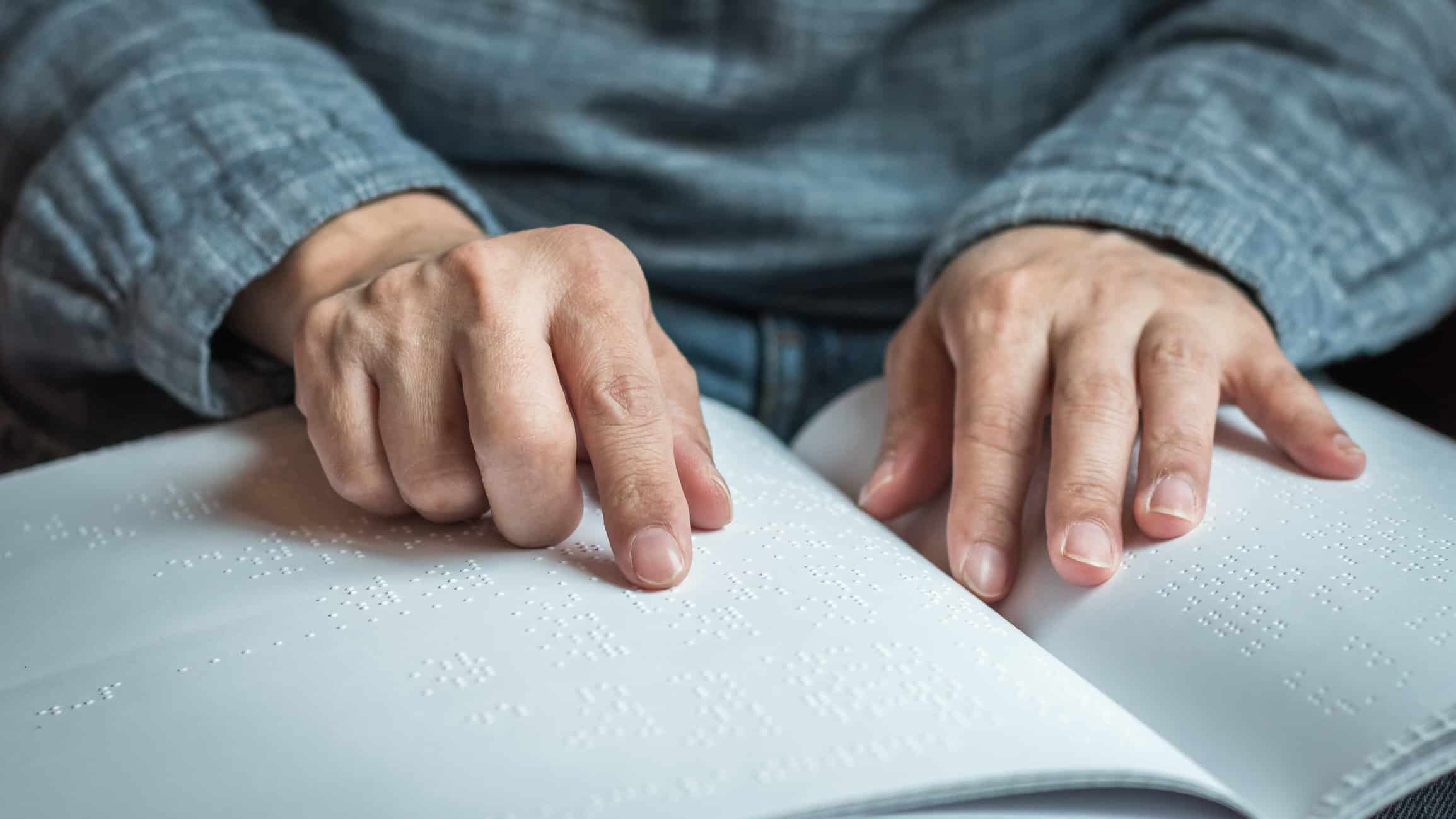 A person reads from a book printed in braille.
