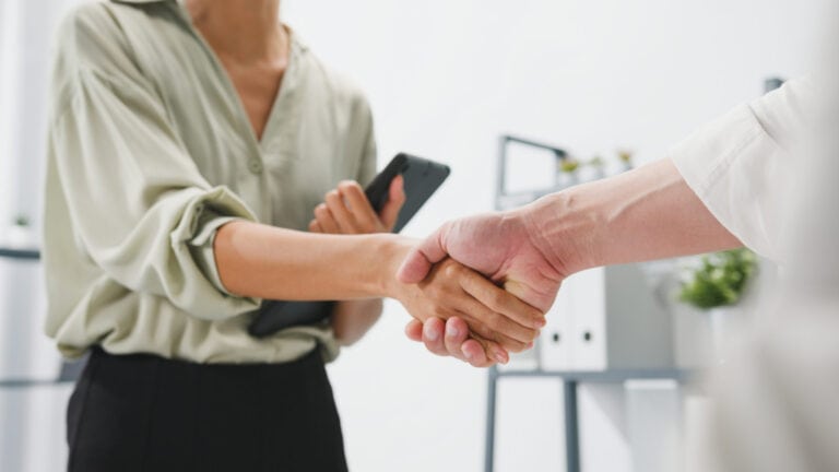 Multiracial pair of young people shaking hands after a job interview.