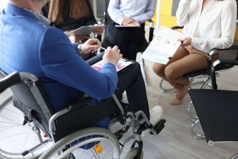 A man in a wheelchair attends a meeting.