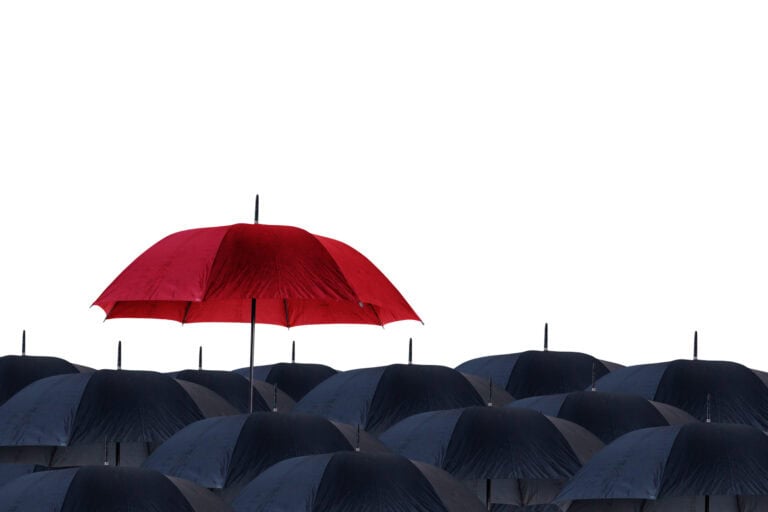 An opened red umbrella held above several open black umbrellas.