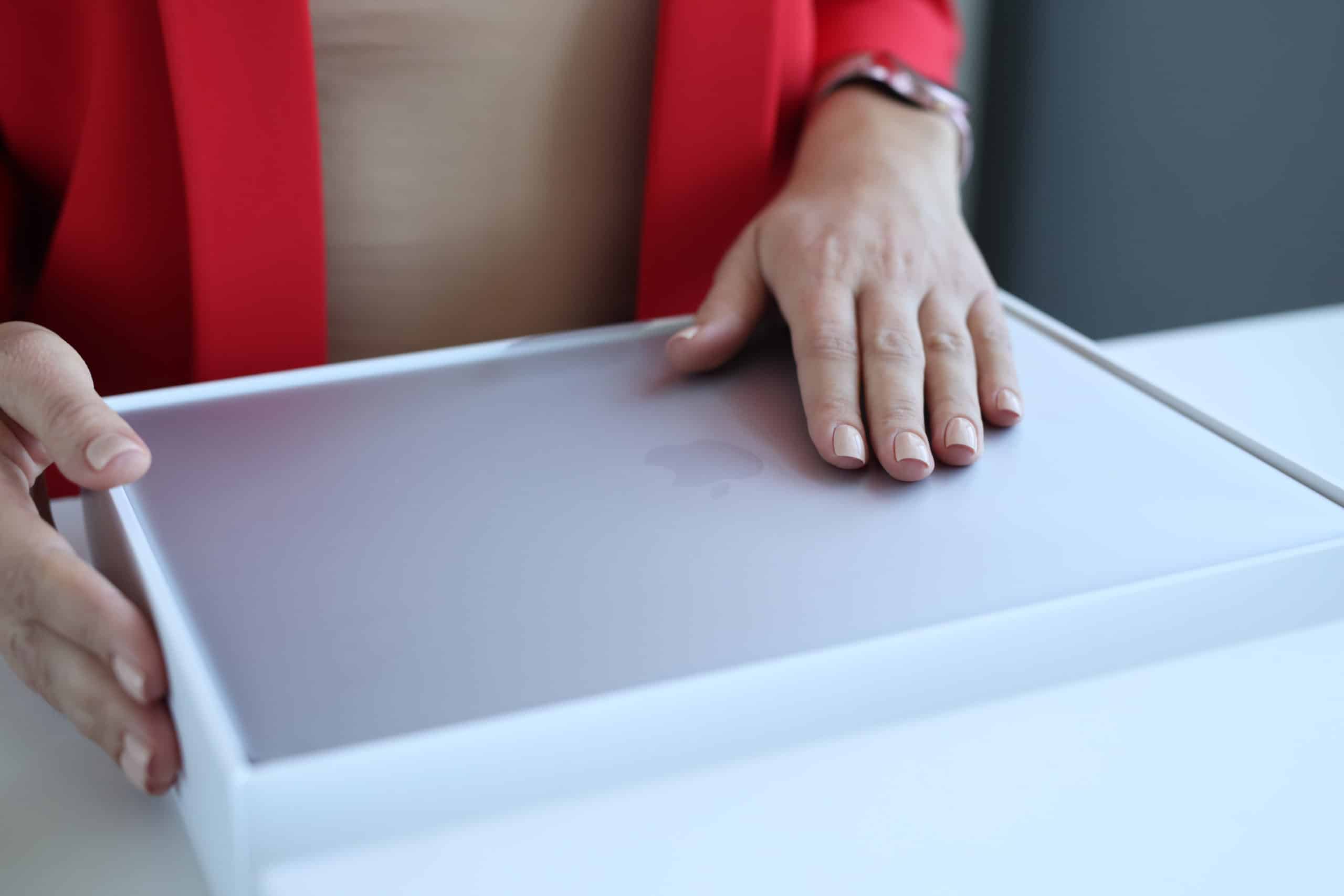 A woman opens a box containing an Apple MacBook Air.