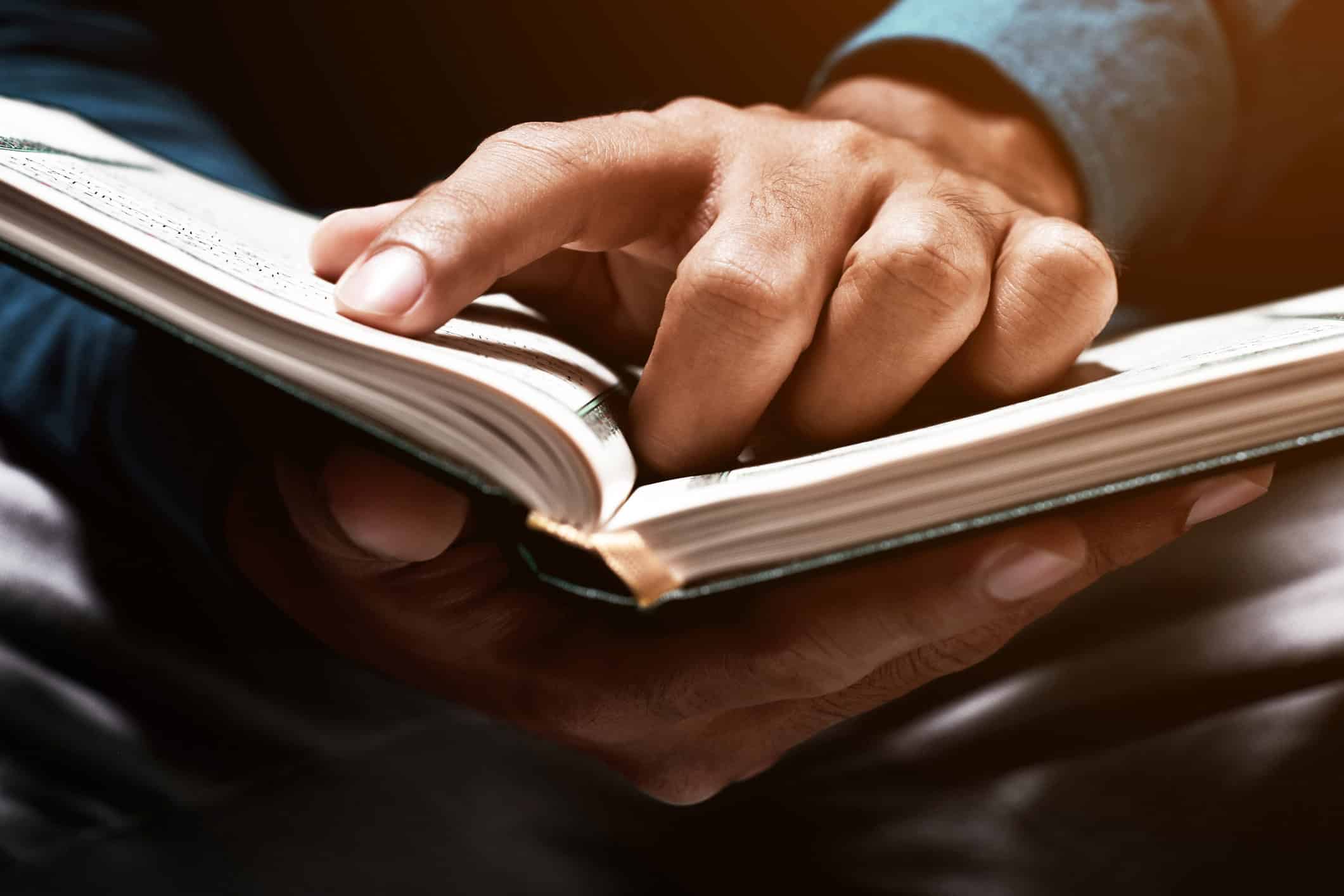 A person holding and reading a Braille book
