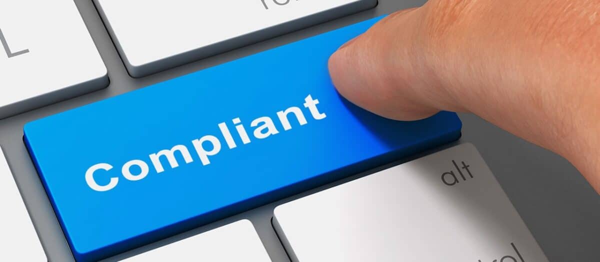 Finger pressing a keyboard key labeled Compliant