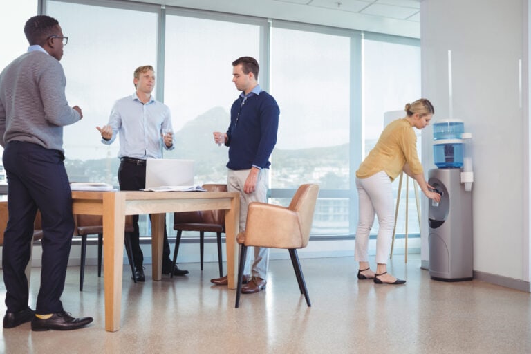 Business colleagues holding drinking glasses while standing at office cafeteria