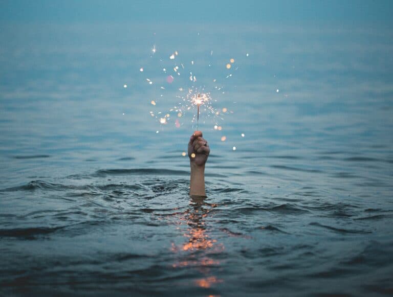 hand reaching out of the water holding a sparkler