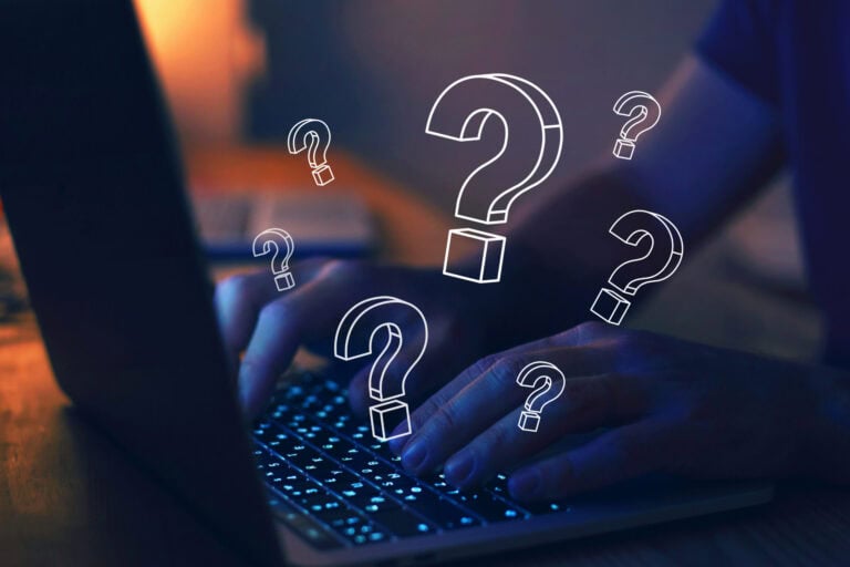 Fingers on laptop keyboard with superimposed question marks all over the image