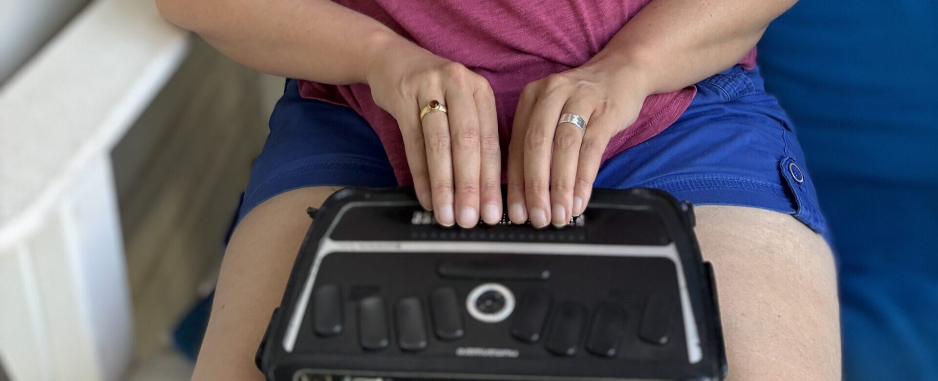 Kristen uses a refreshable Braille display that rests on her lap.